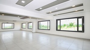 Um quarto amplo e bem iluminado, com janelas grandes, piso ladrilhado e design moderno no teto.