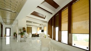Um hall de hotel espaçoso com teto alto, grandes janelas e design moderno e clean.