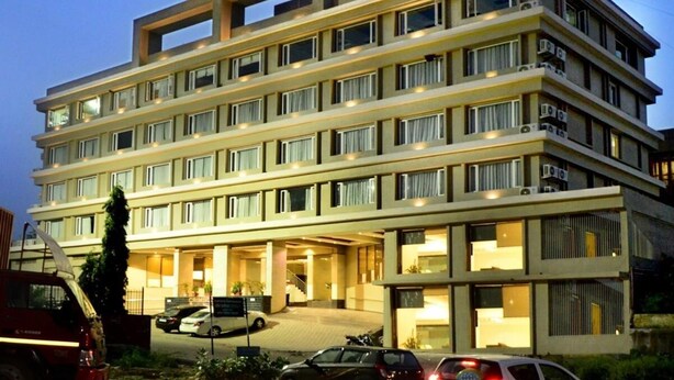 Um hotel com vários andares, fachada plana, janelas amplas e uma placa indicando ser o 