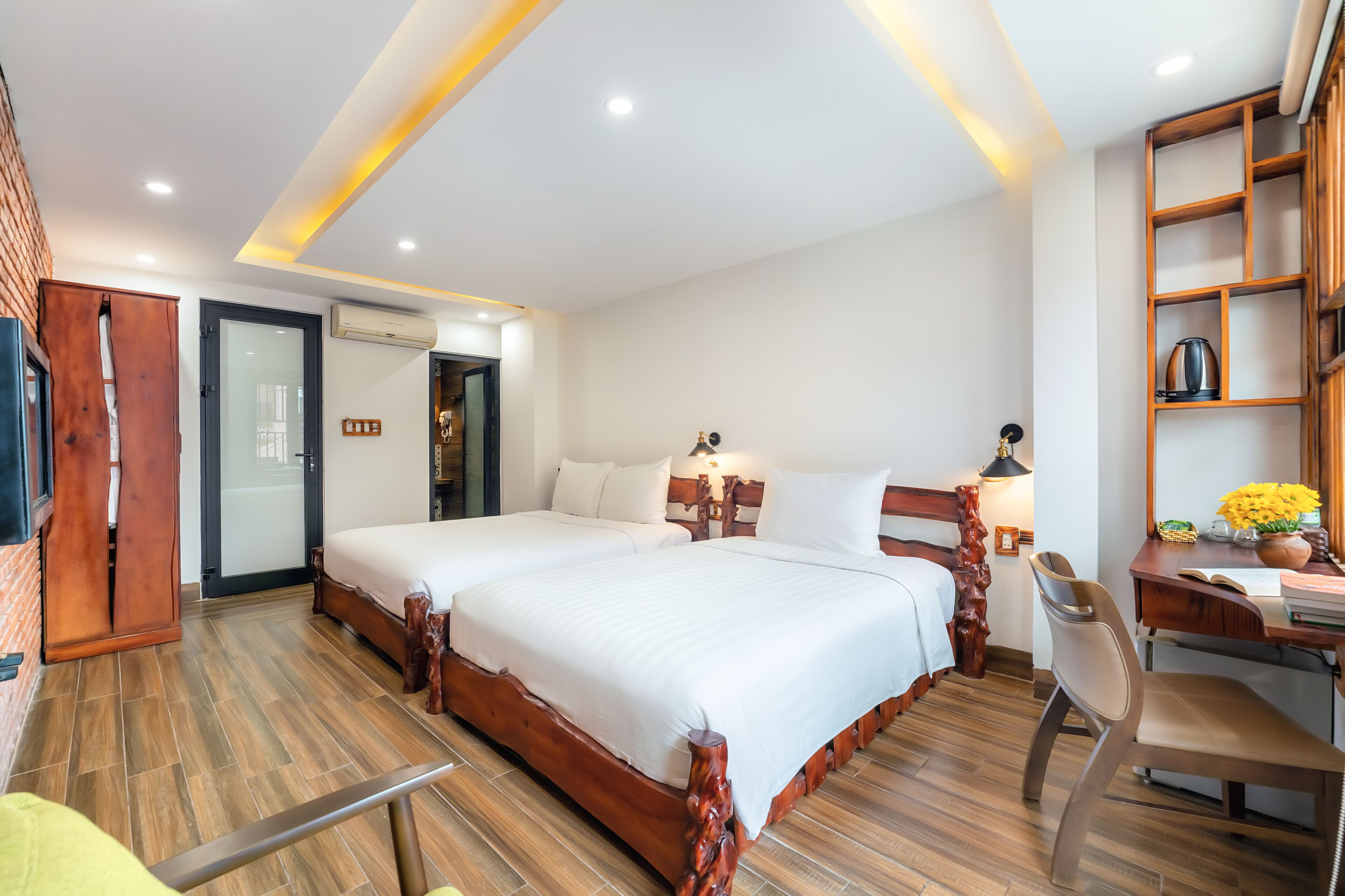 Habitación de hotel con dos camas, un escritorio, una silla y una estantería.