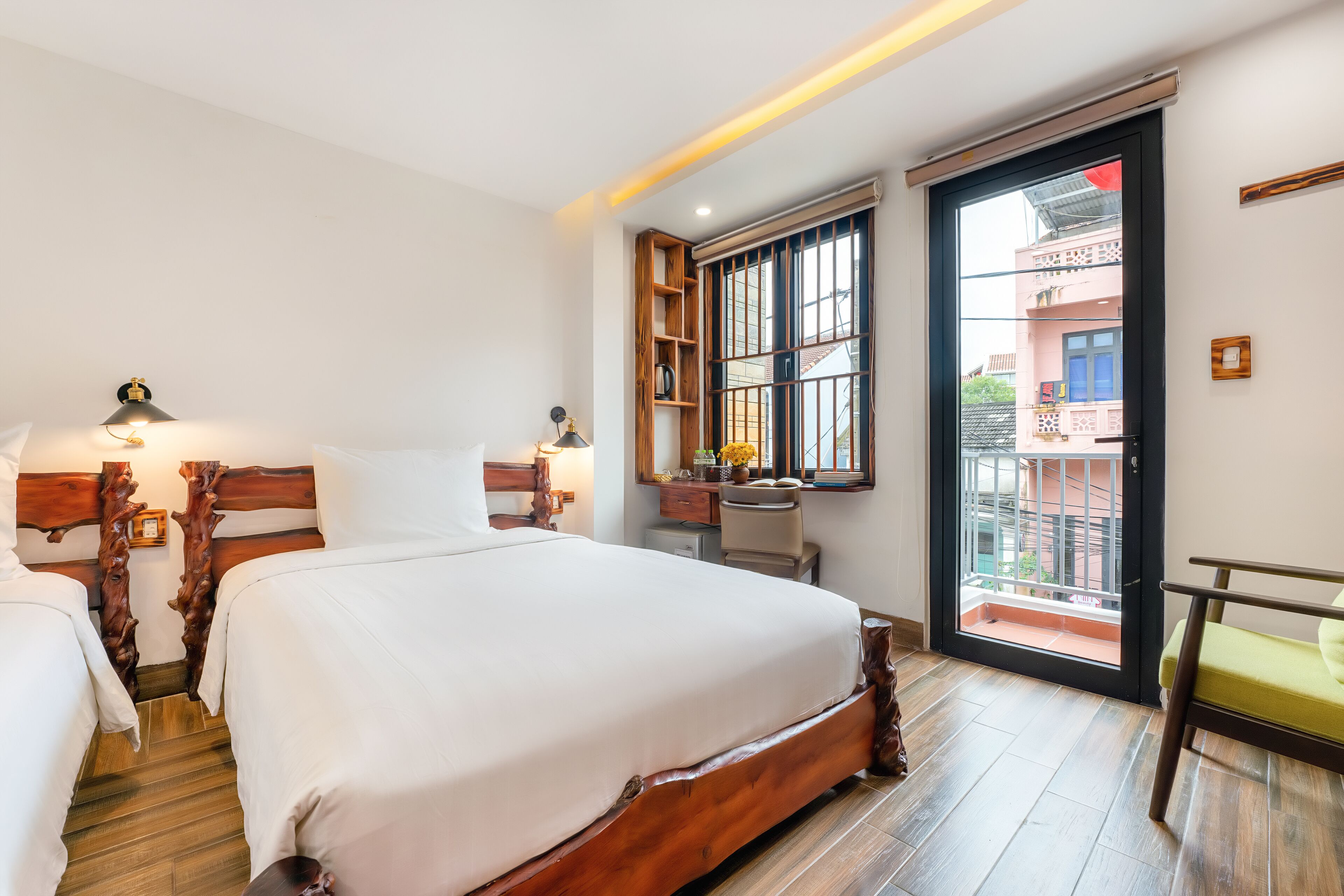 Une chambre d’hôtel avec un grand lit, un bureau, une chaise et une fenêtre donnant sur les bâtiments environnants.