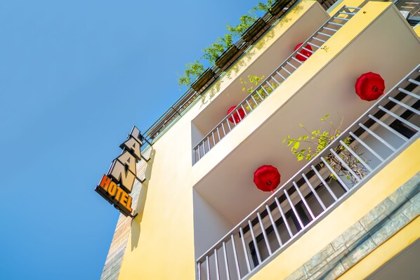 Een hotelschilt met een balkon en rode parasols.