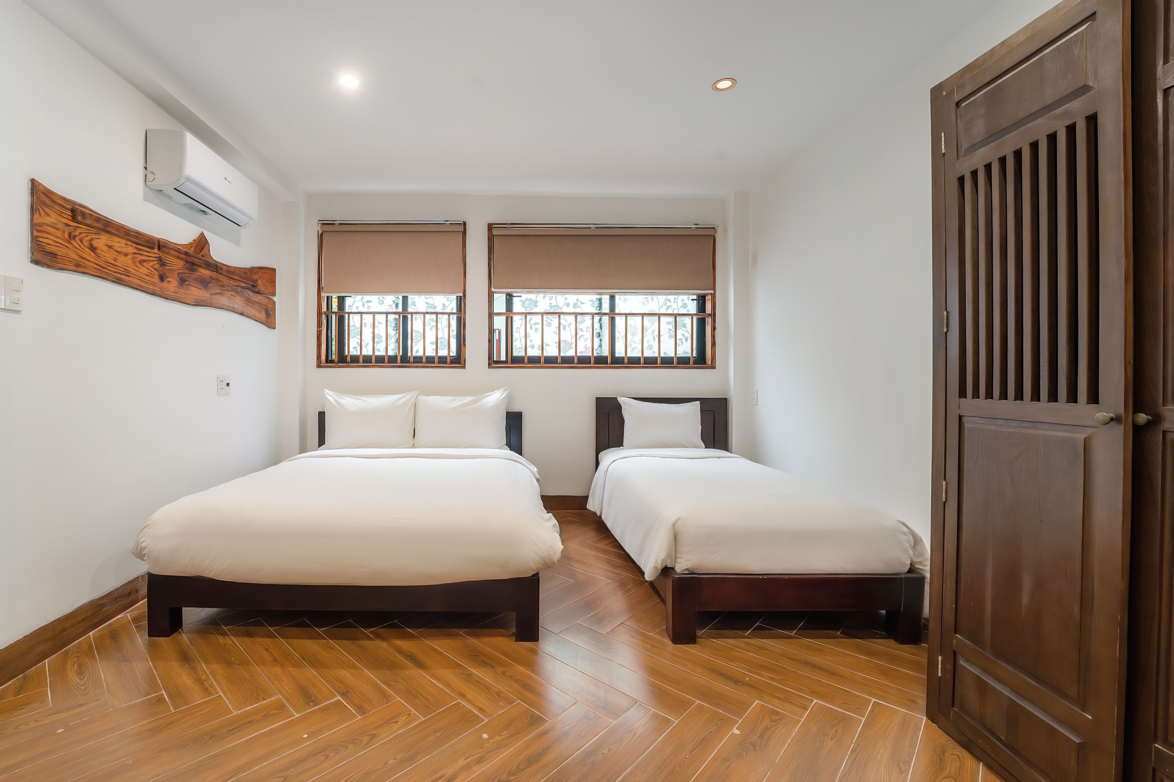 Una habitación con dos camas, suelo de madera y un gran puerta de madera.