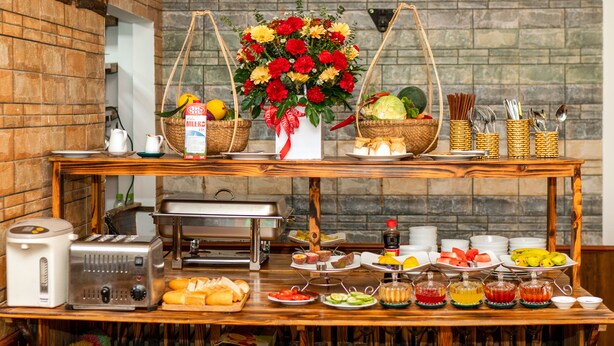Montaje de bufé con diferentes tipos de comida, una máquina de café y un arreglo floral decorativo.