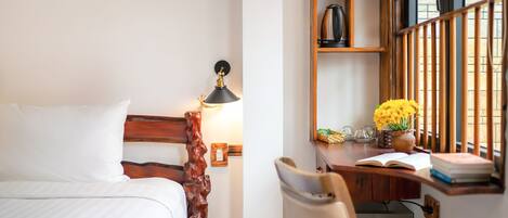 A hotel room with a bed, a desk with a chair, a lamp, and a window with a view.