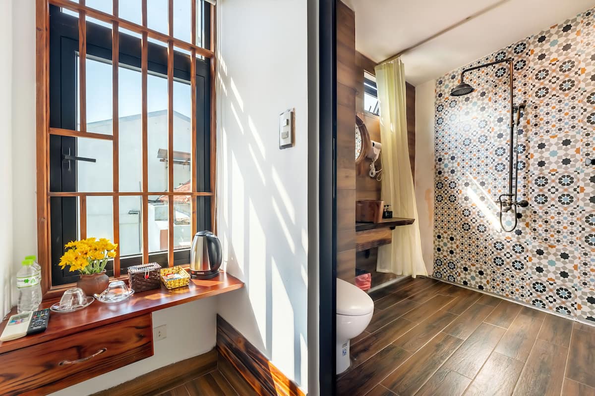 Une salle de bain avec un meuble-lavabo en bois, des toilettes et une douche aux carreaux décorés.
