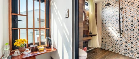 A bathroom with a wooden vanity, a toilet, and a shower with patterned tiles.