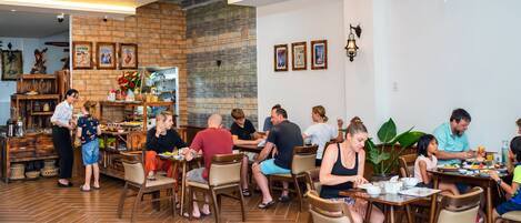 A restaurant with wooden flooring, brick walls, and a variety of seating arrangements including tables and chairs.
