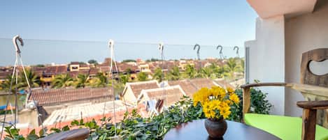 A balcony with a wooden table, a chair, and a potted plant with yellow flowers.