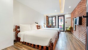 Un dormitorio con dos camas, cabeceros de madera, una pared de ladrillo decorativa, un televisor montado en la pared y un balcón con vistas.