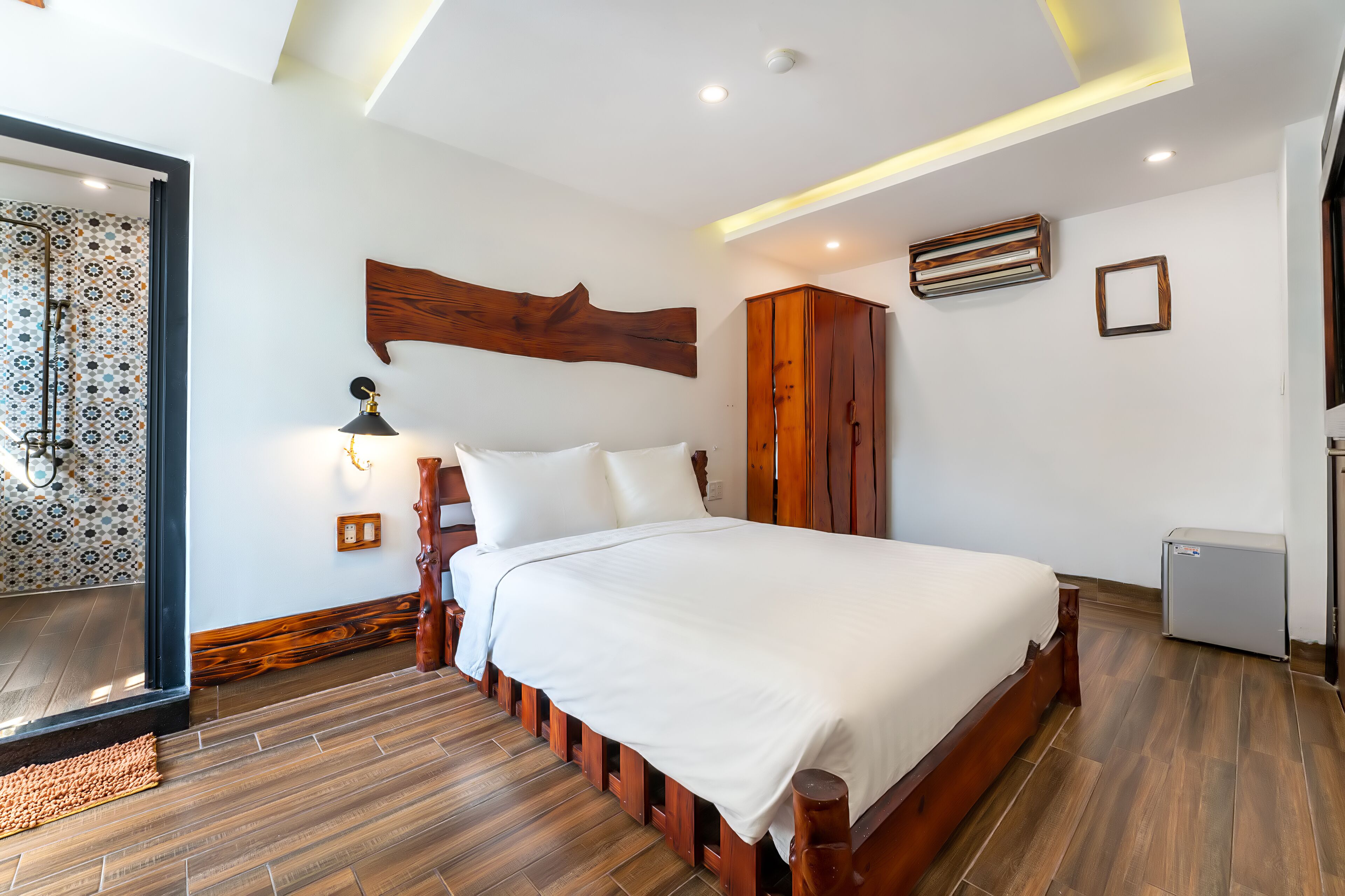 Une chambre moderne avec un grand lit, une tête de lit en bois et une petite table de chevet.