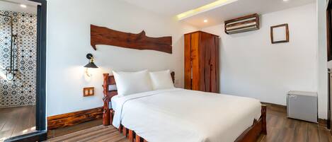 Quarto moderno com cama grande, cabeceira de madeira e mesa de cabeceira pequena.