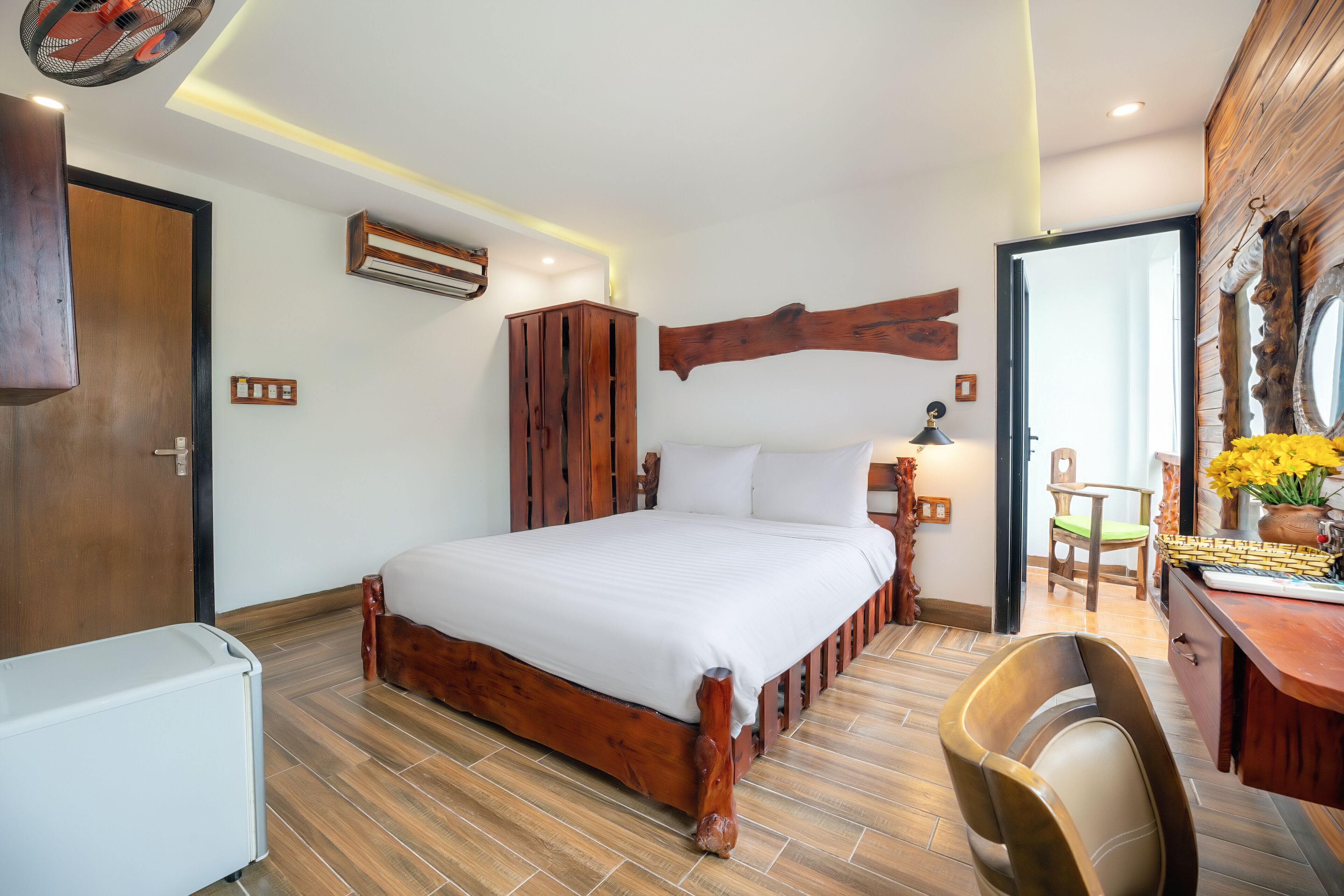 Une chambre à coucher avec un lit en bois, un bureau avec une chaise et un miroir au mur.