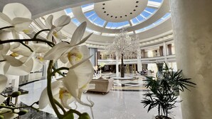 A spacious lobby with a central atrium, a chandelier, and a large tree. - KaiSol Romance Resort (Sahl Hasheeh)