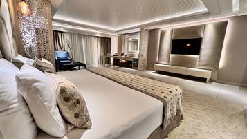 Amplia habitación de hotel con una cama grande, un escritorio, una silla y un televisor.
