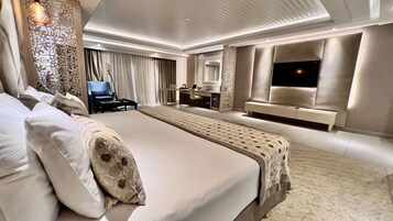 Amplia habitación de hotel con una cama grande, un escritorio, una silla y un televisor.