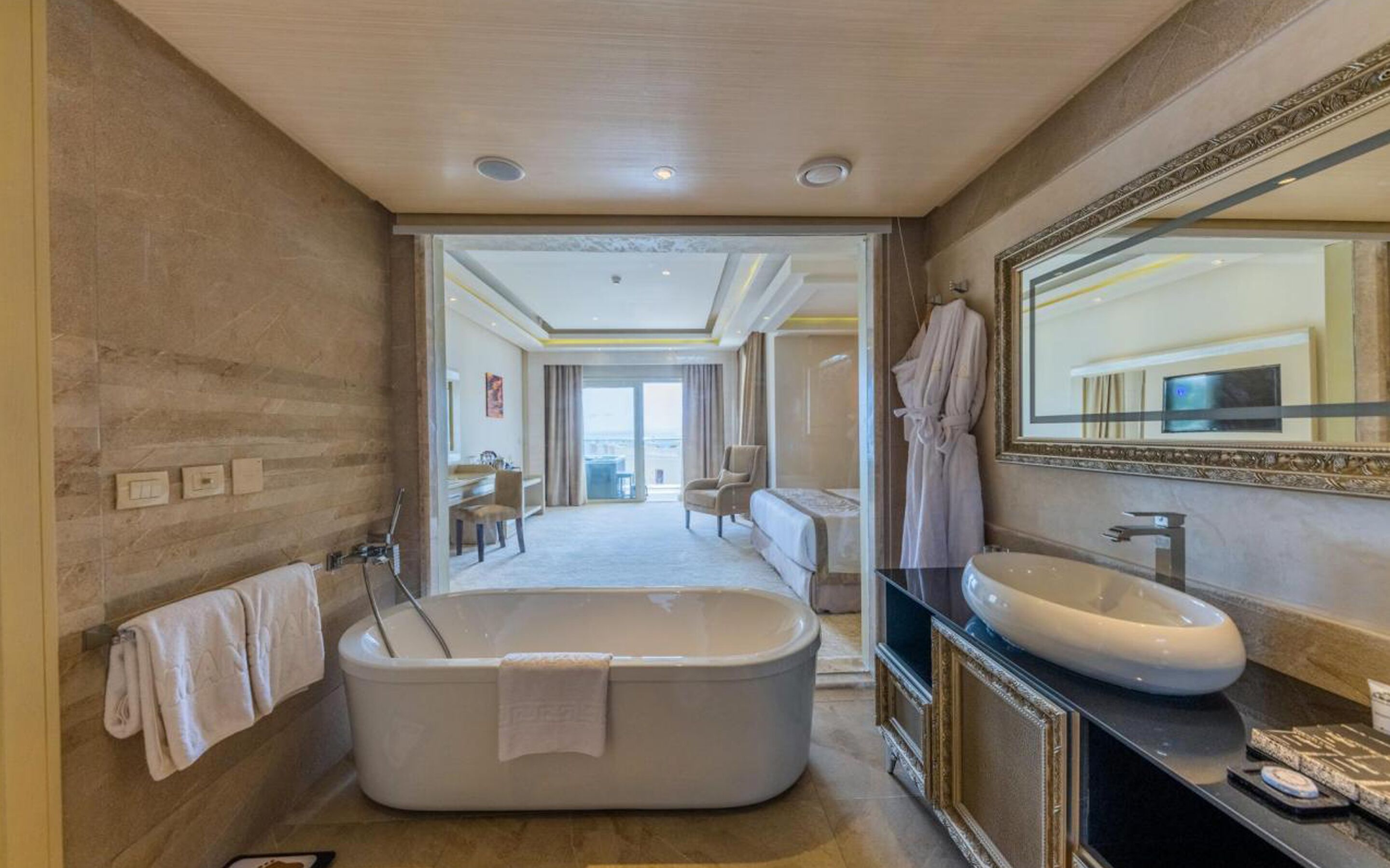 A modern bathroom with a freestanding bathtub, a large mirror, and a vanity with a round sink.