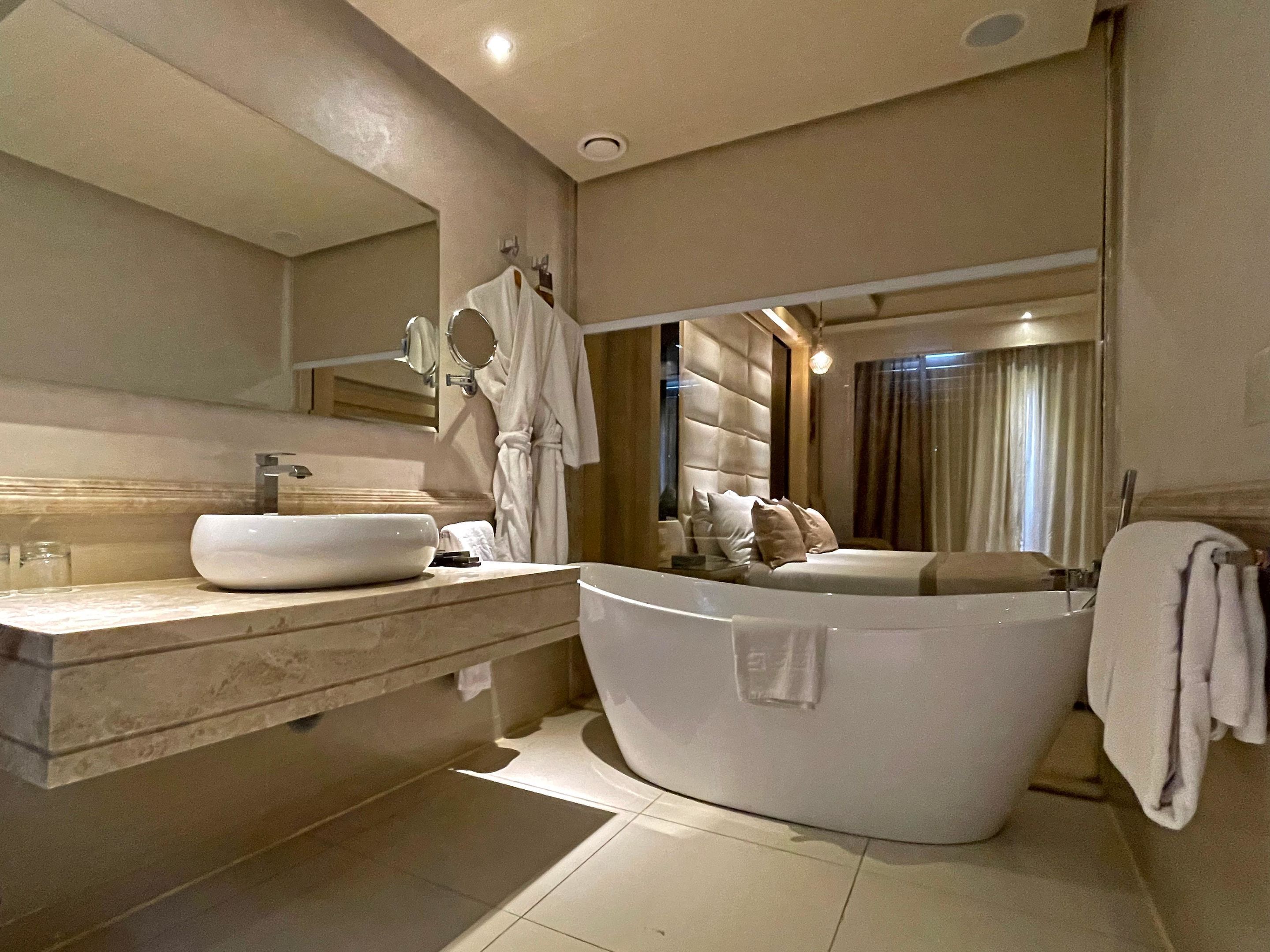 Een moderne badkamer met een groot ligbad, een wastafelmeubel met een ruime wastafel en een spiegel.