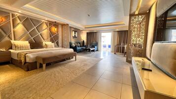 A modern hotel room with a large bed, a seating area, and a TV.