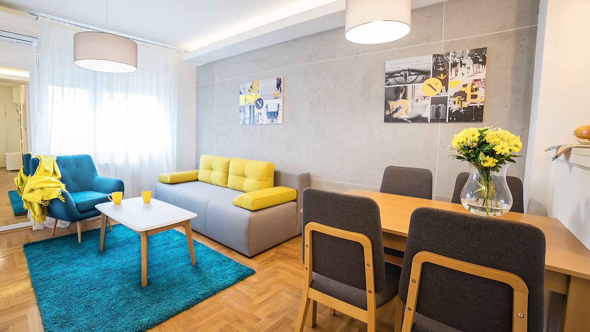 A modern living room with a blue sofa, yellow cushions, a coffee table, and a dining area with chairs and a table.