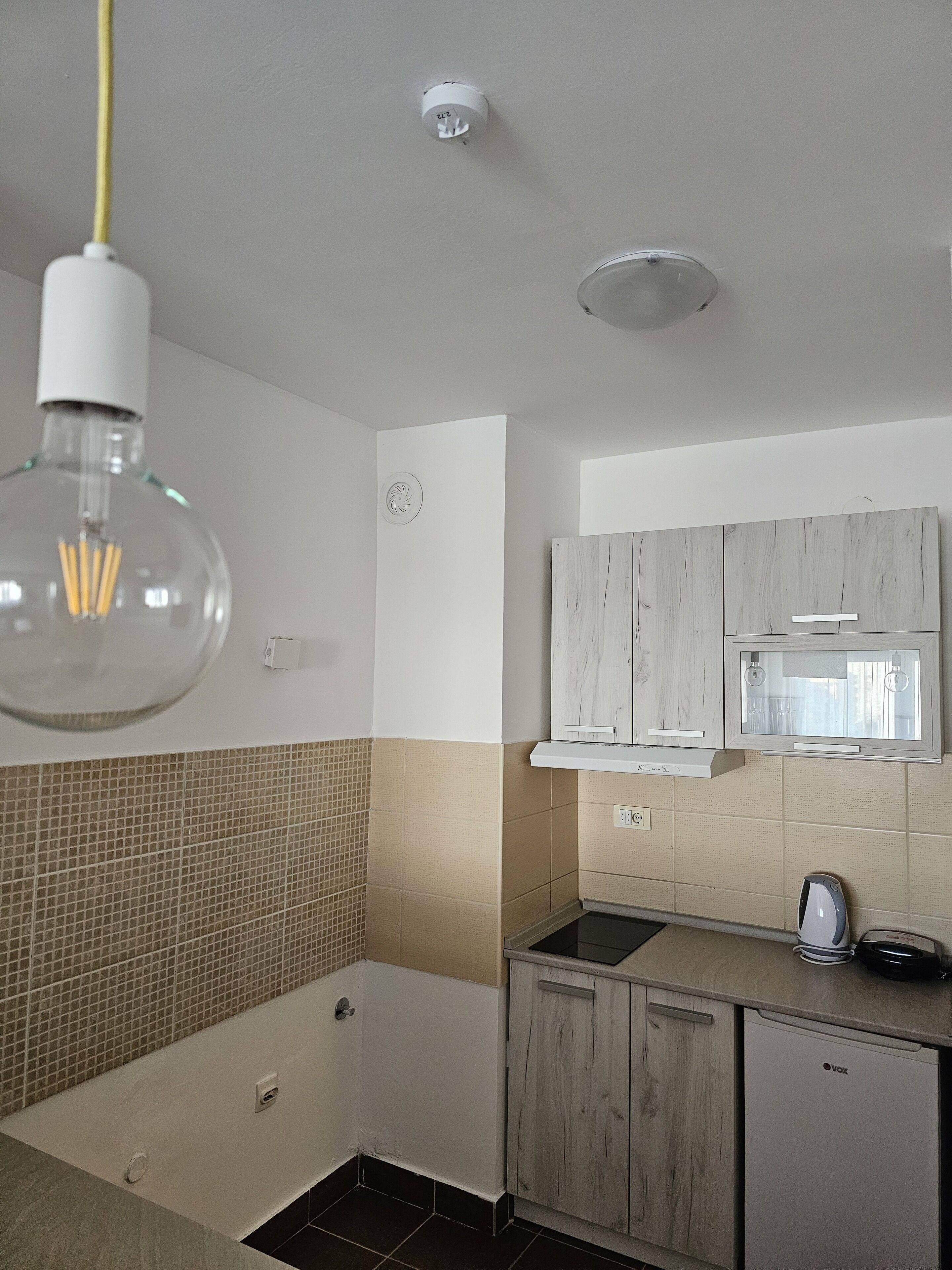 A modern kitchen with a microwave, a kettle, and a dishwasher.