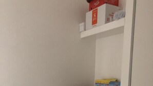 Un coin de pièce avec un sol blanc, un petit panier blanc posé sur un tabouret et une poubelle blanche.