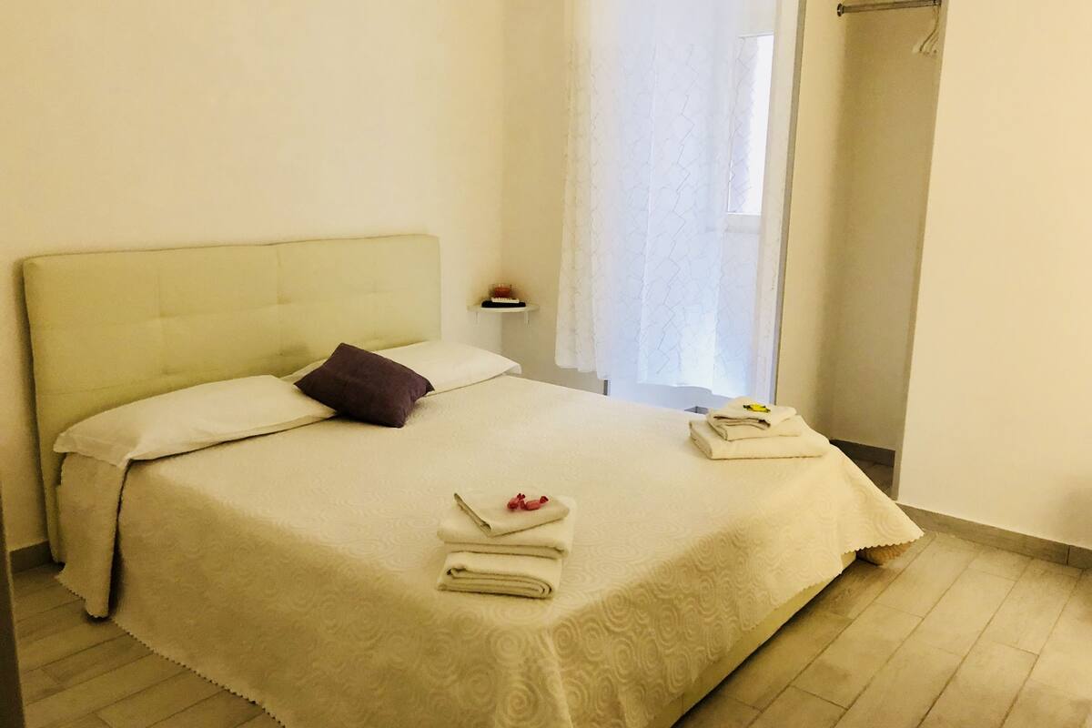 Un letto rifatto con cura, con una testiera, un cuscino e un asciugamano piegato.