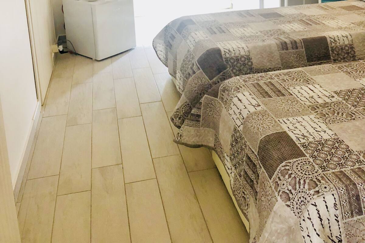 Una camera da letto con un letto, un comodino, uno specchio e una finestra con tende.