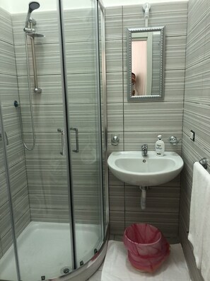 Un baño con ducha de vidrio, lavamanos y espejo.