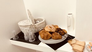 Une table de petit-déjeuner avec des viennoiseries, un panier et un rouleau d’essuie-tout, le tout posé sur un comptoir blanc.