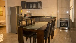 Cozinha moderna com mesa de jantar, cadeiras, geladeira, armários e forno.