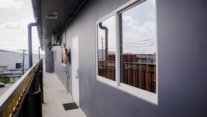 Um corredor com janela para uma área cercada, uma porta e um respiradouro no teto.