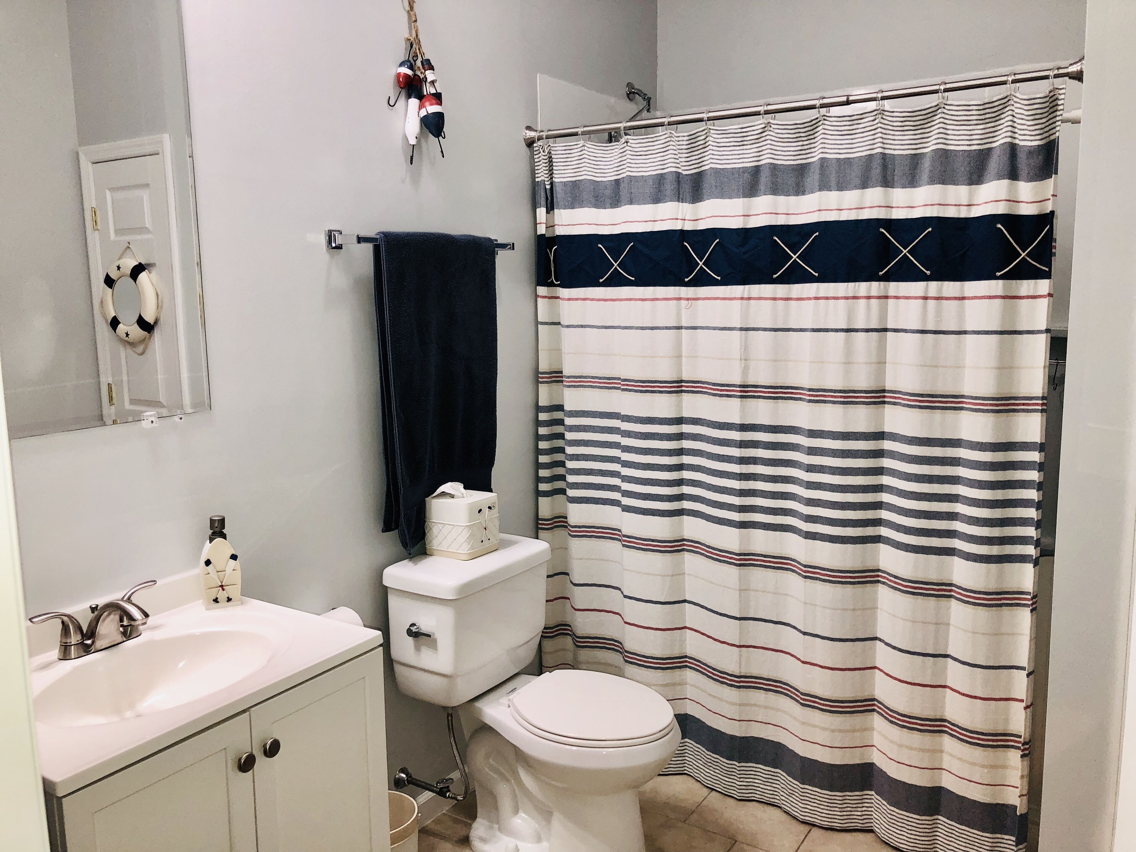 Un baño con lavamanos blanco, inodoro y cortina de ducha a rayas.