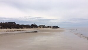 Une plage bordée de maisons, une plage de sable et un ciel nuageux.
