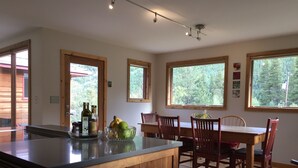 A kitchen with wooden cabinets, a central island, and a dining area with wooden chairs and a table.