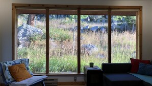 A room with a large window, a sofa, a chair, and a small table.