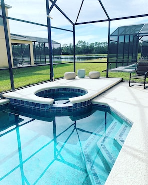 Ein Schwimmbecken mit Whirlpool, umgeben von einer überdachten Terrasse mit Sitzgelegenheiten.