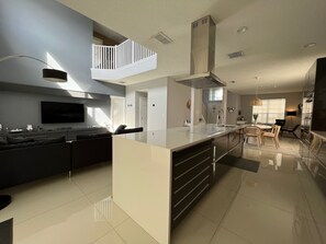 Eine moderne Küche mit Kochinsel, ein Essbereich mit Stühlen und ein Wohnzimmer mit Sofa.