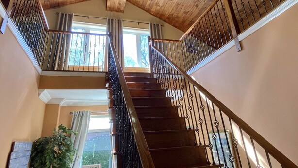 Eine Holztreppe mit schwarzen Geländern und einer Chandelüstere.