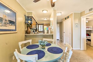 A dining area with a round table, chairs, and a vase of flowers. There is a kitchen in the background with cabinets and a refrigerator. - Ocean View, Pools: Hilton Head Resort: STR 072378 (Hilton Head Island)