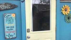Une porte dotée d’un panneau en verre dépoli, avec le chiffre « 9 » au-dessus, et un petit espace de porche comprenant une chaise violette.