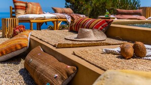 Un salon de plage doté de meubles en osier, de tapis tissés et de coussins aux couleurs vives.