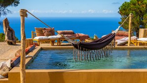 Un espace piscine agr émenté d’un hamac, d’une terrasse en bois et de chaises longues.