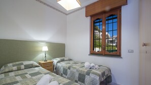 Une chambre avec deux lits, une fenêtre donnant sur un beau paysage, une lampe et une table de chevet.