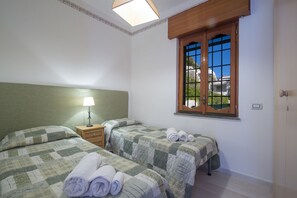 Une chambre avec deux lits, une fenêtre donnant sur un beau paysage, une lampe et une table de chevet.