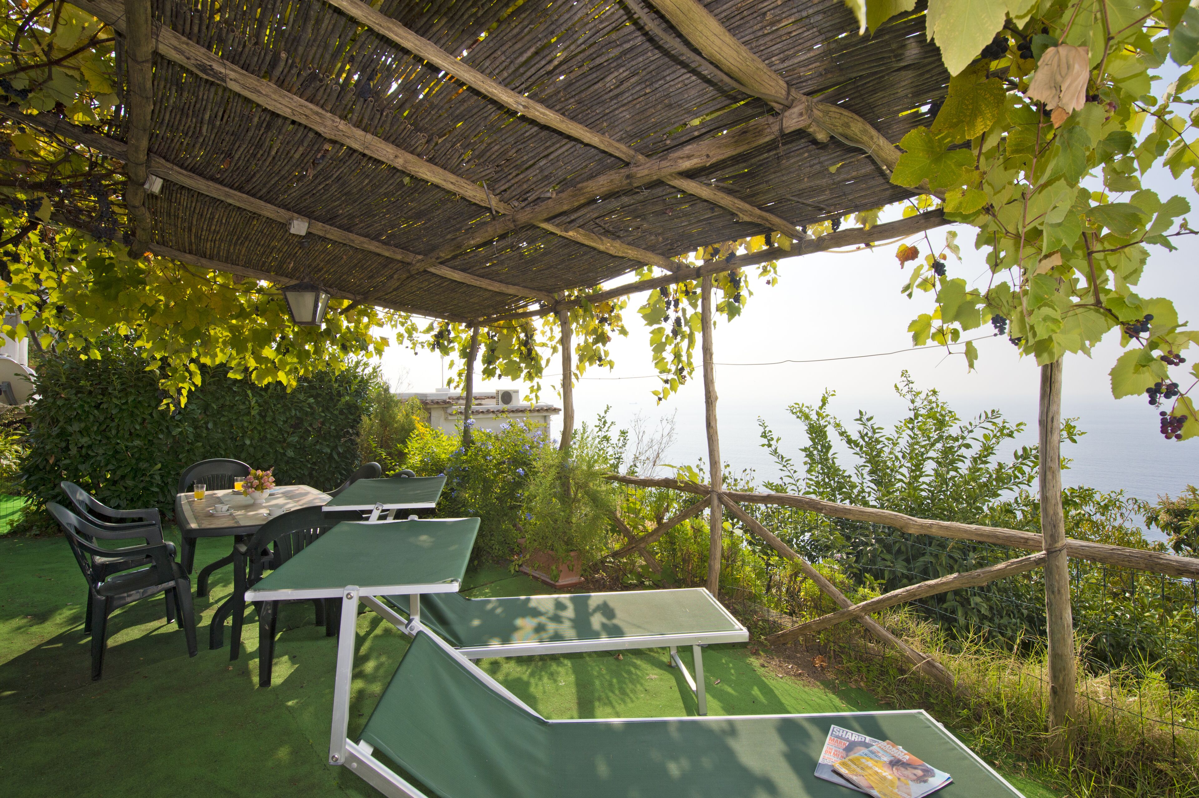Un área de estar al aire libre con mesas y sillas, una estructura de pérgola y vistas al paisaje.