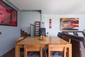 Un salon moderne avec une table à manger en bois, un canapé en cuir marron et un grand tableau abstrait accroché au mur.