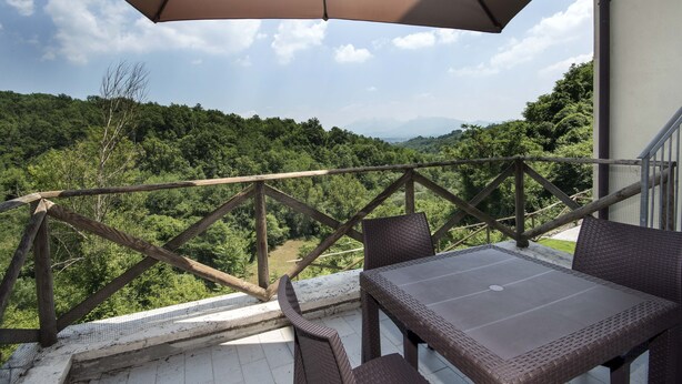 A balcony with a table and chairs, overlooking a forested landscape.