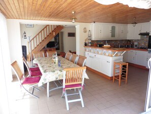 Eine geräumige Küche mit weißen Schränken, einem Holzespeisetisch und einer Treppe, die in eine obere Etage führt.