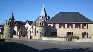 A historic building with a prominent tower and a large main building with a steep roof.